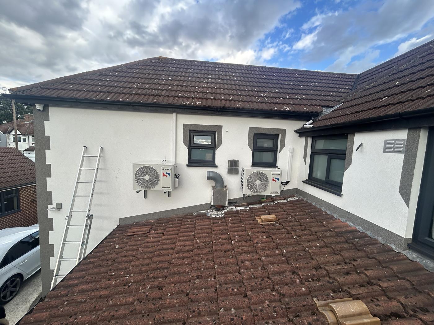 Two Sinclair outdoor units on wall brackets above a flat roof, white trunking to the eaves